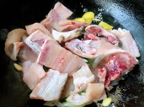另起锅倒入适量油加热放入葱姜蒜爆香再放入鱼骨大火快速翻炒片好的鱼片清洗干净沥干水份