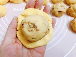 取一份外皮面团压扁包入一份馅料，一边包一边压直到馅料被完全包裹住，收口滚圆