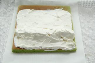 毛巾面在下，修出斜边，奶油均匀抹在卷上，尾部留一点不抹，1/3处排上奶冻条，用淡奶油把奶冻周围空隙填满。