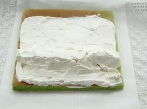 毛巾面在下，修出斜边，奶油均匀抹在卷上，尾部留一点不抹，1/3处排上奶冻条，用淡奶油把奶冻周围空隙填满。