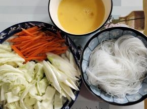 包菜切成条状，胡萝卜切成丝，大葱斜切成片，鸡蛋打散，泡软的粉丝捞出沥干水分备用！