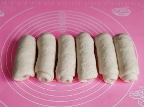 取一块面团擀长舌状再卷起来，盖上保鲜膜松弛5分钟。