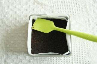 奥利奥饼干碎放入保鲜袋略微擀细，黄油隔热水融化成液态。两者混合拌匀。方盘垫入油纸，拌匀的饼干倒入压平压结实。