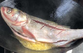 起锅热油，放入鲢鱼，先放鱼头煎一下再放全鱼，先不要翻动