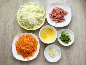 各种食材洗净，包菜、胡萝卜、火腿肠分别切丝，小葱切成葱花，大蒜切成末