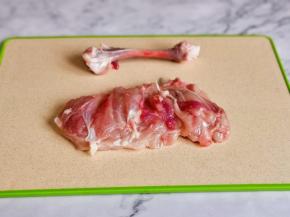 鸡腿放在砧板上，用刀在鸡腿中间划一下，取出骨头。