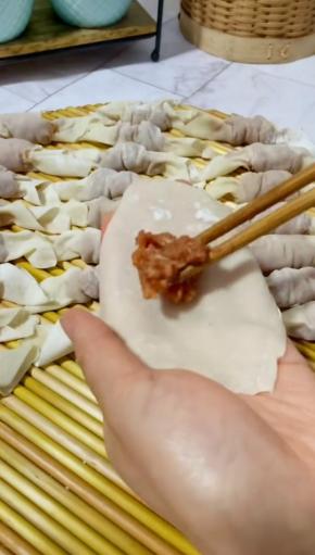 取一张馄饨皮，放入4~5克馄饨馅儿！