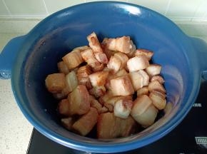 焯水后的五花肉清洗两边，沥干水份，锅里放一点油，放五花肉煸炒至两面金黄。