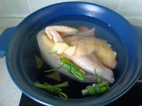 三黄鸡冷水下锅，加入生姜，葱结。