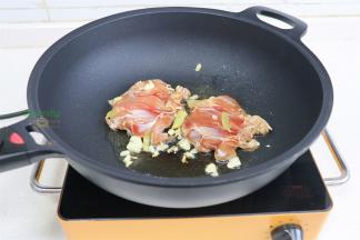 锅烧热，倒入少许油，放大蒜煸炒香，放入鸡腿肉，鸡皮朝下。