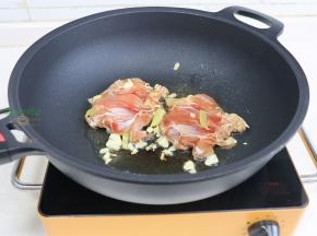 锅烧热，倒入少许油，放大蒜煸炒香，放入鸡腿肉，鸡皮朝下。