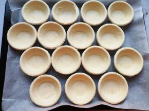 蛋挞皮提前解冻，烤盘里铺上油纸，摆好蛋挞皮。 