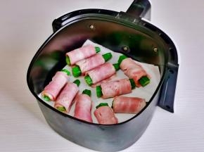 空气炸锅中垫上油纸，放上秋葵培根卷。