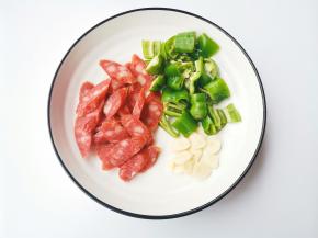 青椒洗净切块，腊肠切斜片，大蒜切片。