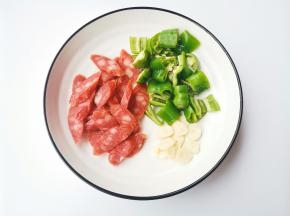 青椒洗净切块，腊肠切斜片，大蒜切片。