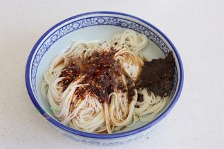 把干香风味肉酱、芽菜、辣油调味料、骨汤。全部倒入面条的碗里，搅拌均匀。盐焗黄豆粒要到热水之后放，可以保持黄豆的酥脆，如果想吃软香的黄豆，可以先放黄豆，再倒沸水。
