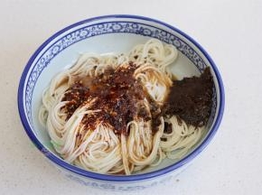 把干香风味肉酱、芽菜、辣油调味料、骨汤。全部倒入面条的碗里，搅拌均匀。盐焗黄豆粒要到热水之后放，可以保持黄豆的酥脆，如果想吃软香的黄豆，可以先放黄豆，再倒沸水。
