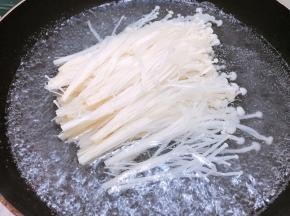 锅里烧水，水开后放入金针菇煮熟后捞出铺在煲底