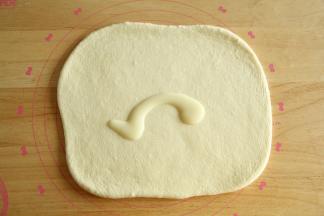 冷冻期间，蔓越莓切碎备用。取出冻好的面团，擀开成长方形面片，刷上一层炼乳。