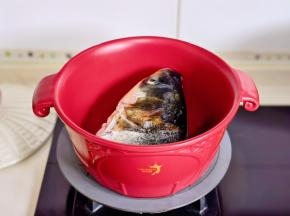 起油锅加入鱼头煎至微黄。