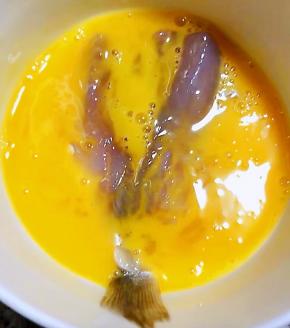 煨制入味的黄花鱼放入打散的蛋液中蘸匀