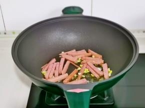 起油锅，加入蒜末炒香，加入切好的香肠条煸炒。