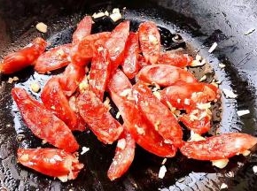 另起锅倒入底油加热放入蒜粒爆香再放入腊肠炒出香味