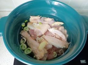 把三黄鸡放入锅里，加生姜，葱段，料酒焯水。