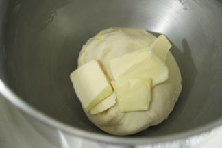 面团略光滑，加盐和软化好的黄油。2档打到黄油与面团混合，转4-5档搅打至出薄膜。
