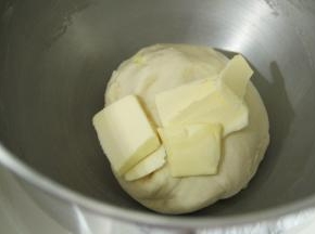 面团略光滑，加盐和软化好的黄油。2档打到黄油与面团混合，转4-5档搅打至出薄膜。