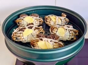 大闸蟹翻过来放在蒸屉上，每只蟹上放一片姜，整15分钟，关火焖2分钟。