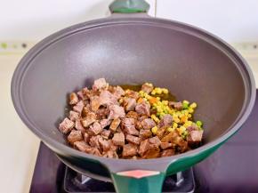 起油锅加入牛肉粒，玉米粒，胡萝卜丁，豌豆翻炒。