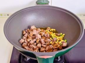 起油锅加入牛肉粒，玉米粒，胡萝卜丁，豌豆翻炒。