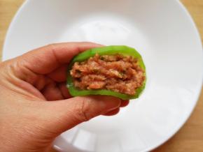 取一片萝卜，放上肉馅，用手轻轻捏一下（如图）。