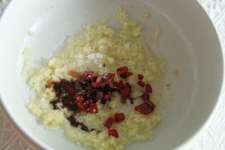 预热烤箱上下200度。不粘锅中加2-3勺玉米油，大火将油烧热后关火，倒入蒜泥翻炒爆香，然后加切碎的辣椒、2勺生抽、糖1勺、盐1勺、黑胡椒粉适量。