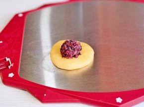 取一块面团掌心压扁，放上紫米馅。