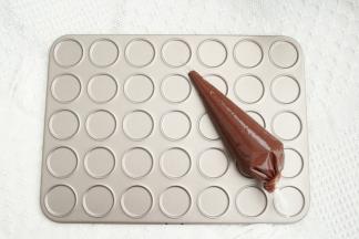 面糊倒入裱花袋中，尾部打结。准备35连模。预热烤箱上下180度。