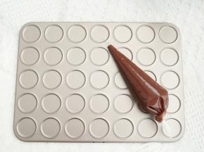 面糊倒入裱花袋中，尾部打结。准备35连模。预热烤箱上下180度。