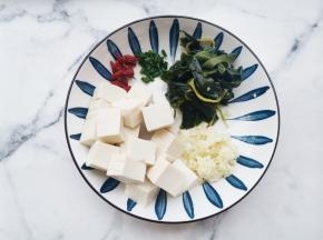 裙带菜提前十分钟泡发洗净切段。豆腐切小块。