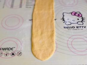 取一块面团，擀长舌装，由上向下卷起来。