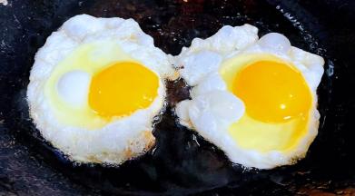 锅中倒入底油加热打入两个鸡蛋中火煎起来