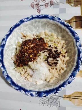 把切好的萝卜丁放入碗中，放入一大勺刚做好的辣椒油，少许刚炸的花椒粒，再放入一勺糖，中合一下辣味！