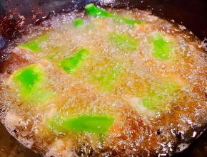 锅中倒入适量油加热放入尖椒酿肉大火炸起来炸至尖椒起虎皮状漂浮起来猪肉馅成金黄色即可出锅