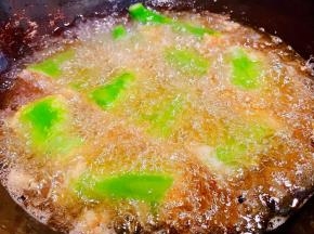 锅中倒入适量油加热放入尖椒酿肉大火炸起来炸至尖椒起虎皮状漂浮起来猪肉馅成金黄色即可出锅