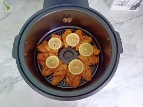 腌制好的鸡翅均匀地码在空气炸锅里，放上柠檬片。