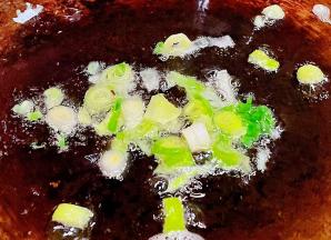 另起锅倒入少许底油加热放入香葱爆香