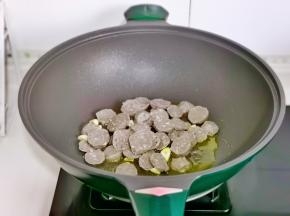 起油锅，加入蒜片炒香，再加入牛肉丸子片煸炒。