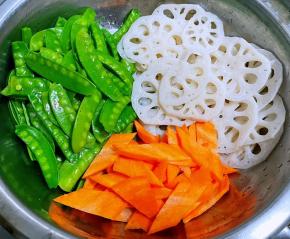 处理好的藕片、荷兰豆切好的胡萝卜片放入容器中备用