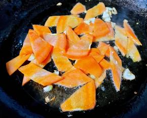 锅中倒入底油加热放入蒜片爆香再放入胡萝卜片炒至断生