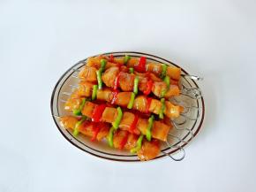 腌制好的鸡块与青红椒用不锈钢签子串起来，每个肉串刷一层食用油，防止烤好的肉串表面变干。